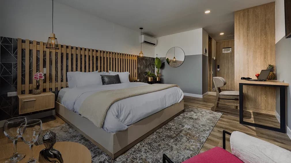 Habitación de GO Living Suites, marca que el grupo impulsa como Growth partner de venta directa sin operarla, con cama tendida, escritorio y panel de listones de madera.