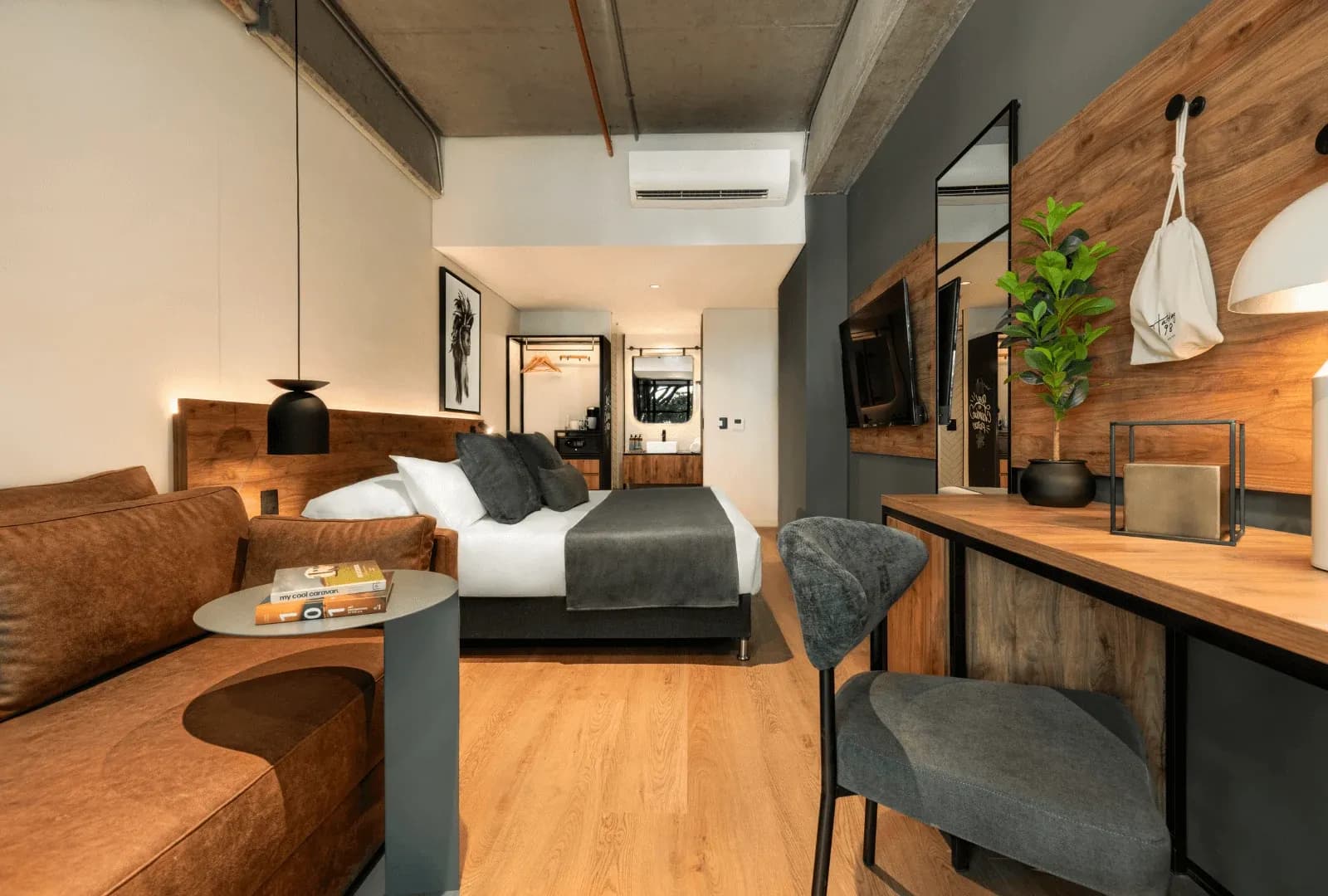 Habitación de Hashtag 98, marca que el grupo impulsa como Growth partner de venta directa sin operarla, con cama tendida con estándar hotelero, sofá y escritorio de madera.