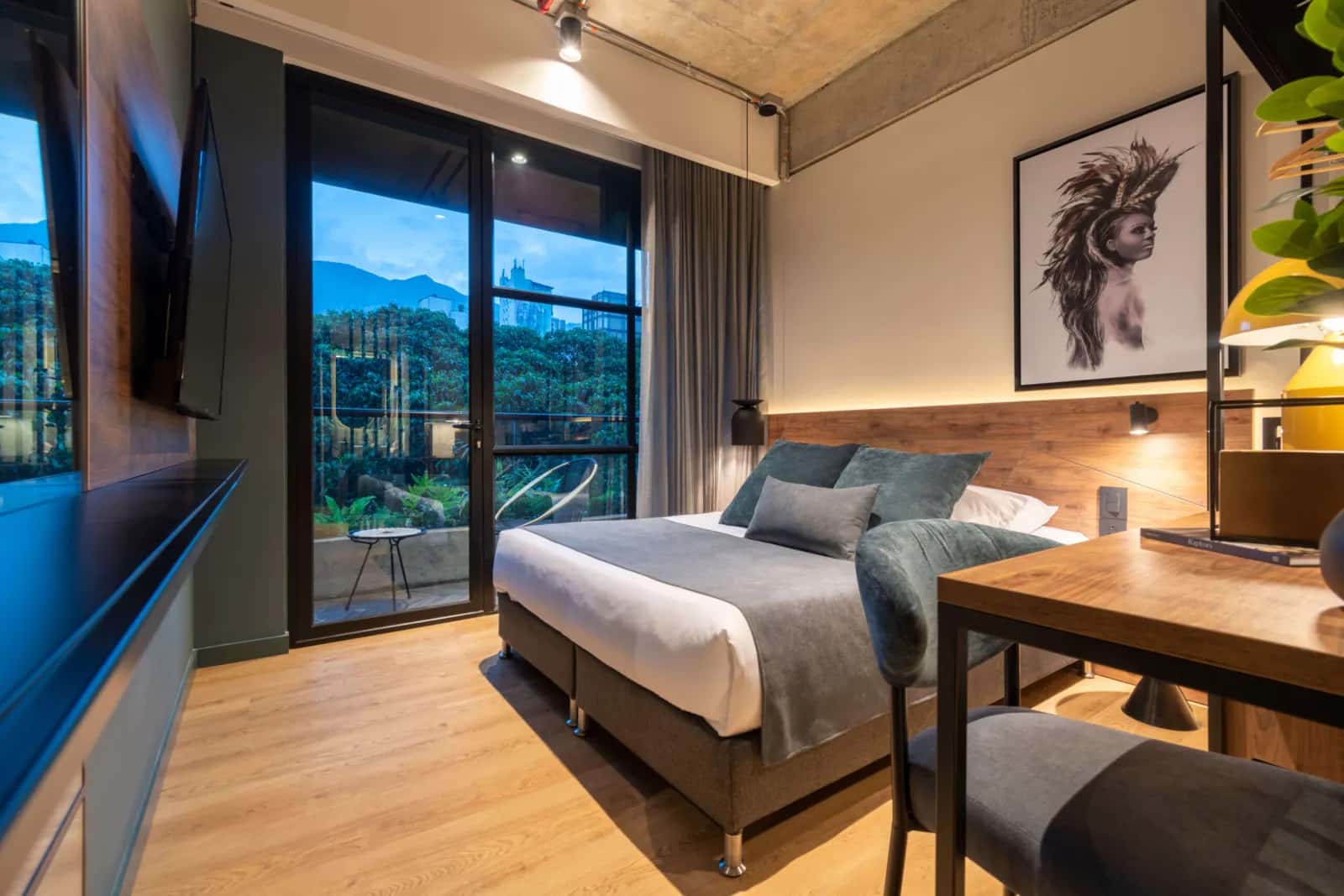Habitación de Hashtag 98, marca que el grupo impulsa como Growth partner de venta directa sin operarla, con cama tendida, luz cálida y ventanal al balcón al atardecer.